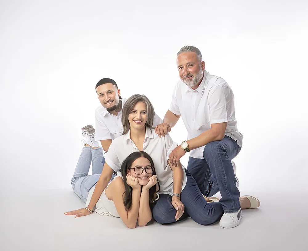 Family of four in white shirts and denim on a studio floor