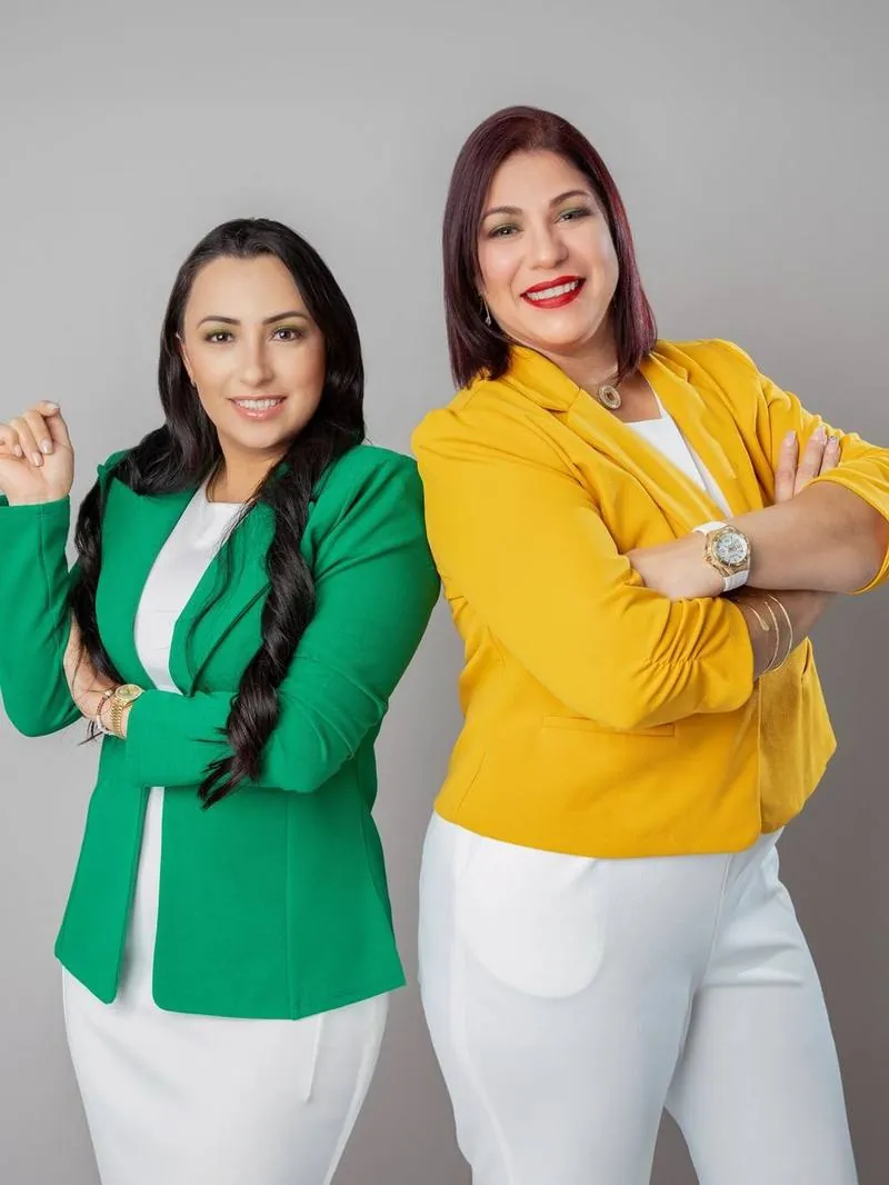 Two business partners in green and yellow blazers smiling in a studio headshot