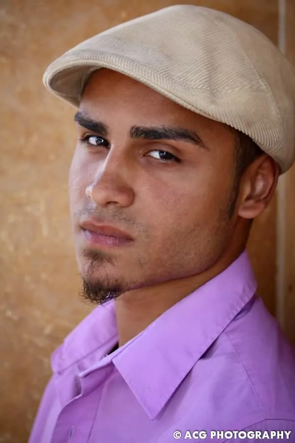 Studio headshot of a man in a newsboy cap