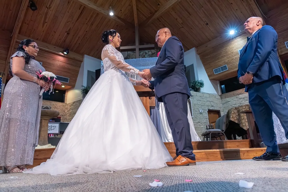 A bride and groom hold hands at the altar during their church wedding ceremony
